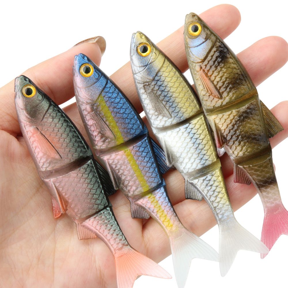 Four soft swimbaits in different colours held in a hand