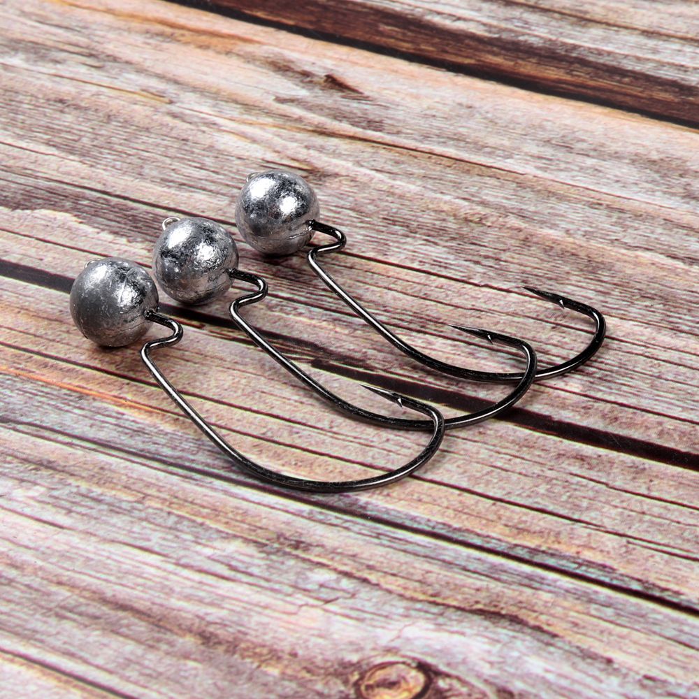Three weighted jig head hooks on a wooden surface